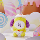 Yellow Chimmy plush toy with purple ears, wearing a bib, against a candy-themed backdrop.