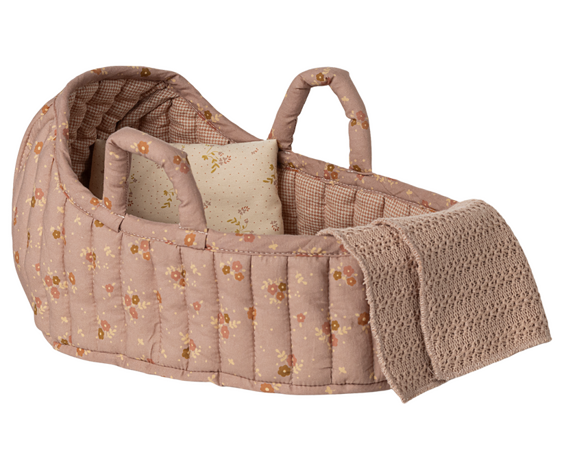 Pink floral quilted doll bassinet with pillow and knitted blanket.