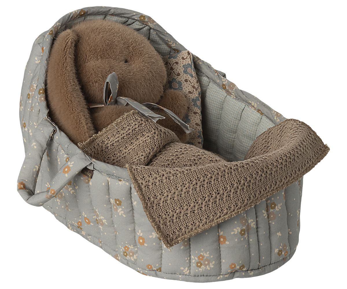 Stuffed bunny in floral print quilted bassinet with knit blanket.