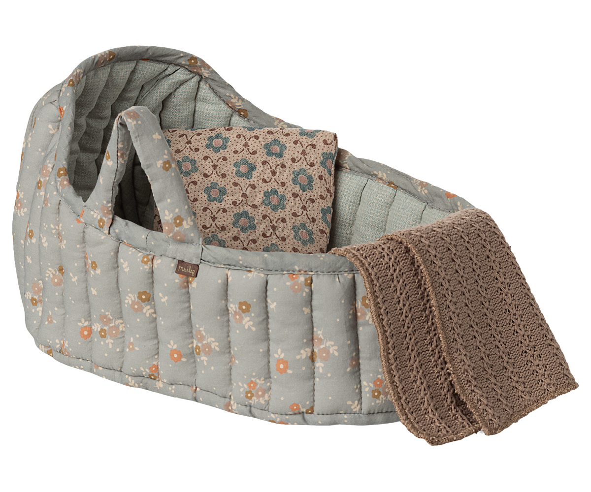 Quilted floral baby bassinet with pillow and knit blanket.