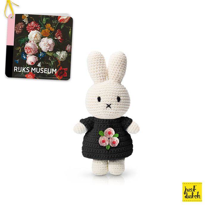 Crocheted Miffy doll wearing a black dress with pink flower embellishments, next to a book titled "Rijksmuseum".