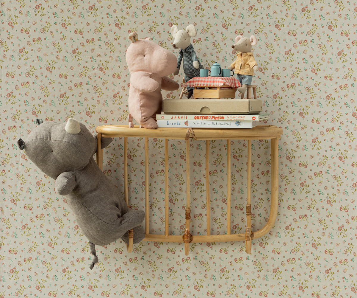 Stuffed animals on a light wood shelf against a floral wallpaper backdrop.