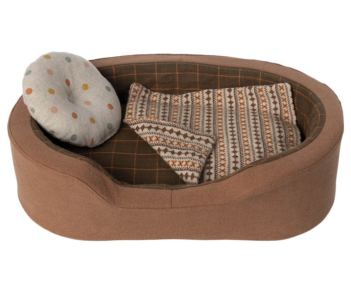 Brown dog bed with pillow and blanket.