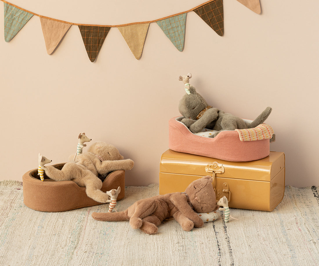 Stuffed animals in beds and resting. Neutral colors. Playful setting.