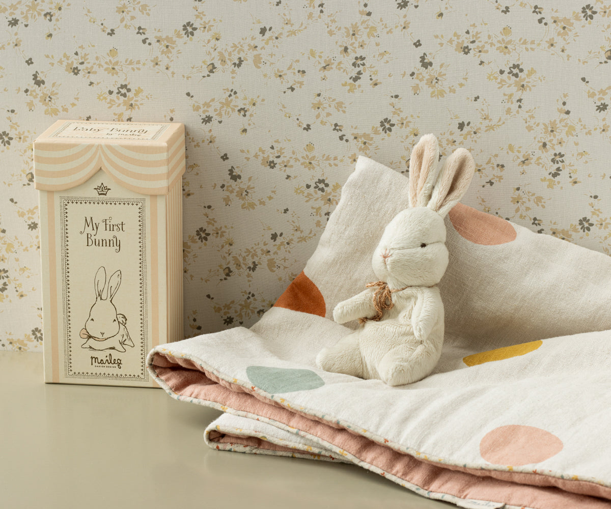 Stuffed bunny on a polka-dot blanket next to a "My First Bunny" box.