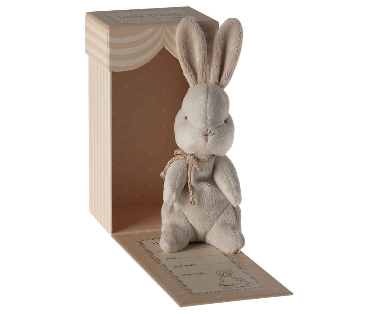 Stuffed grey bunny in a striped box.