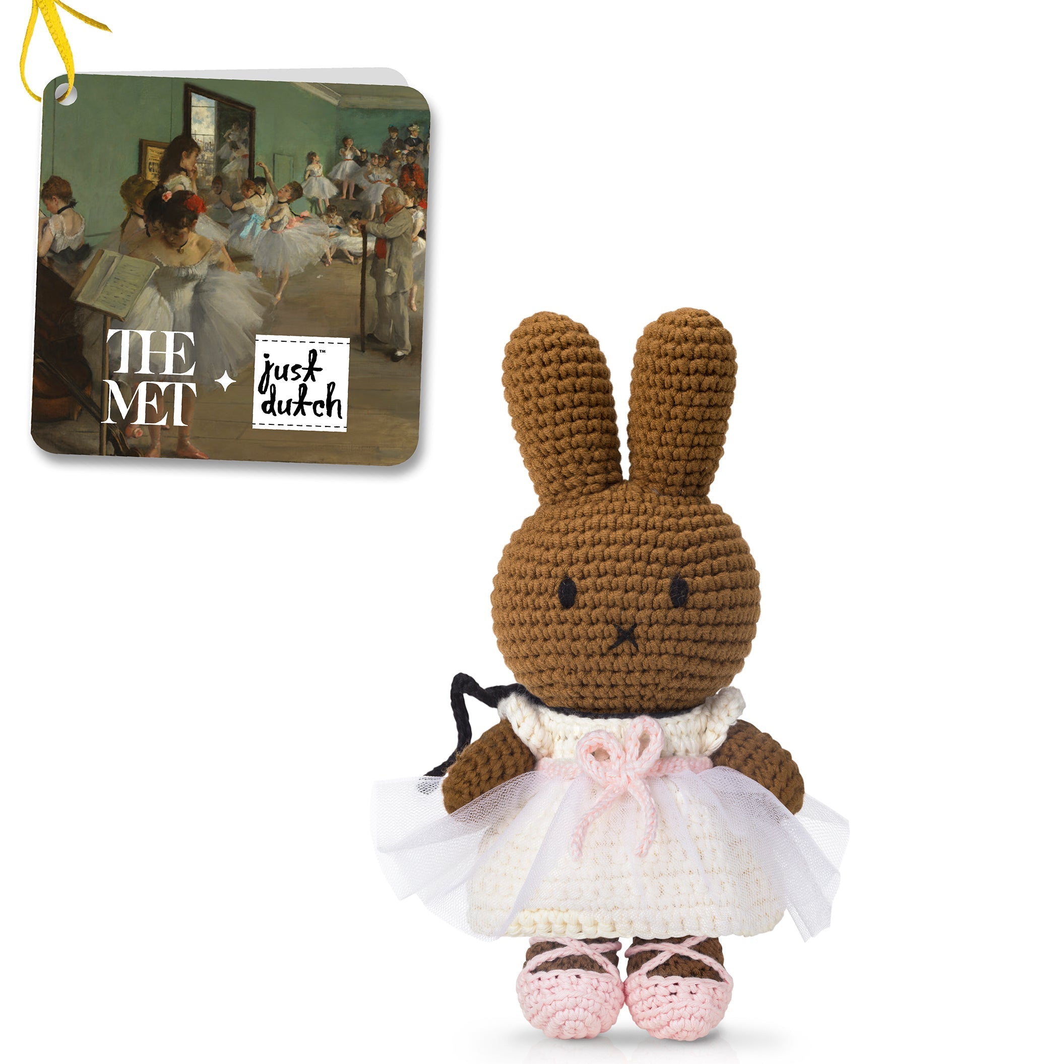 Crocheted brown bunny ballerina in a white dress with pink details, featuring a tag with art and brand logos.