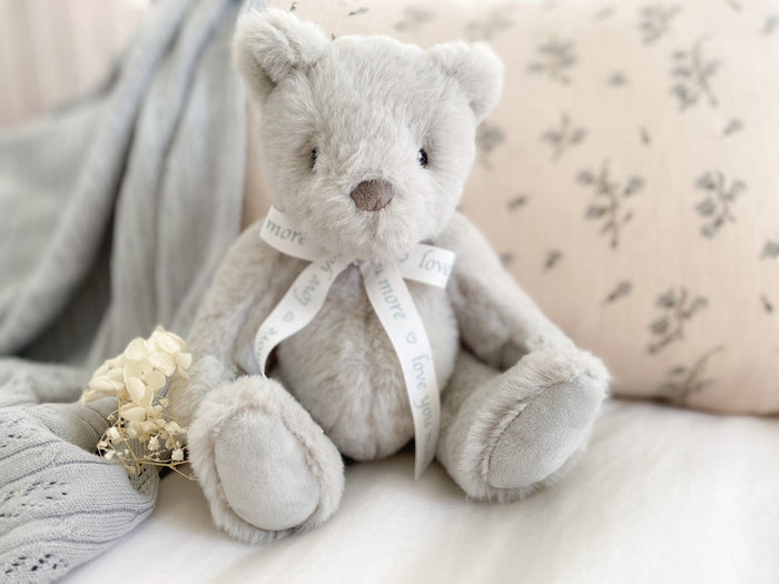 Gray teddy bear with a ribbon on a soft surface
