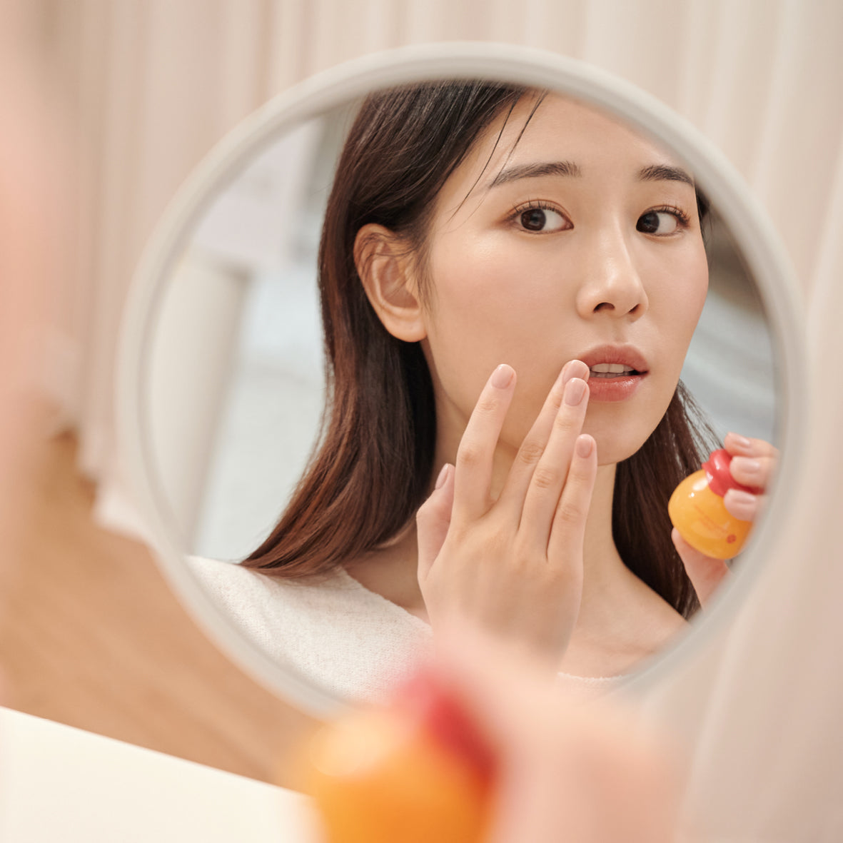 Reflection of a woman applying lip balm.