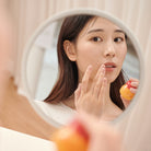 Reflection of a woman applying lip balm.