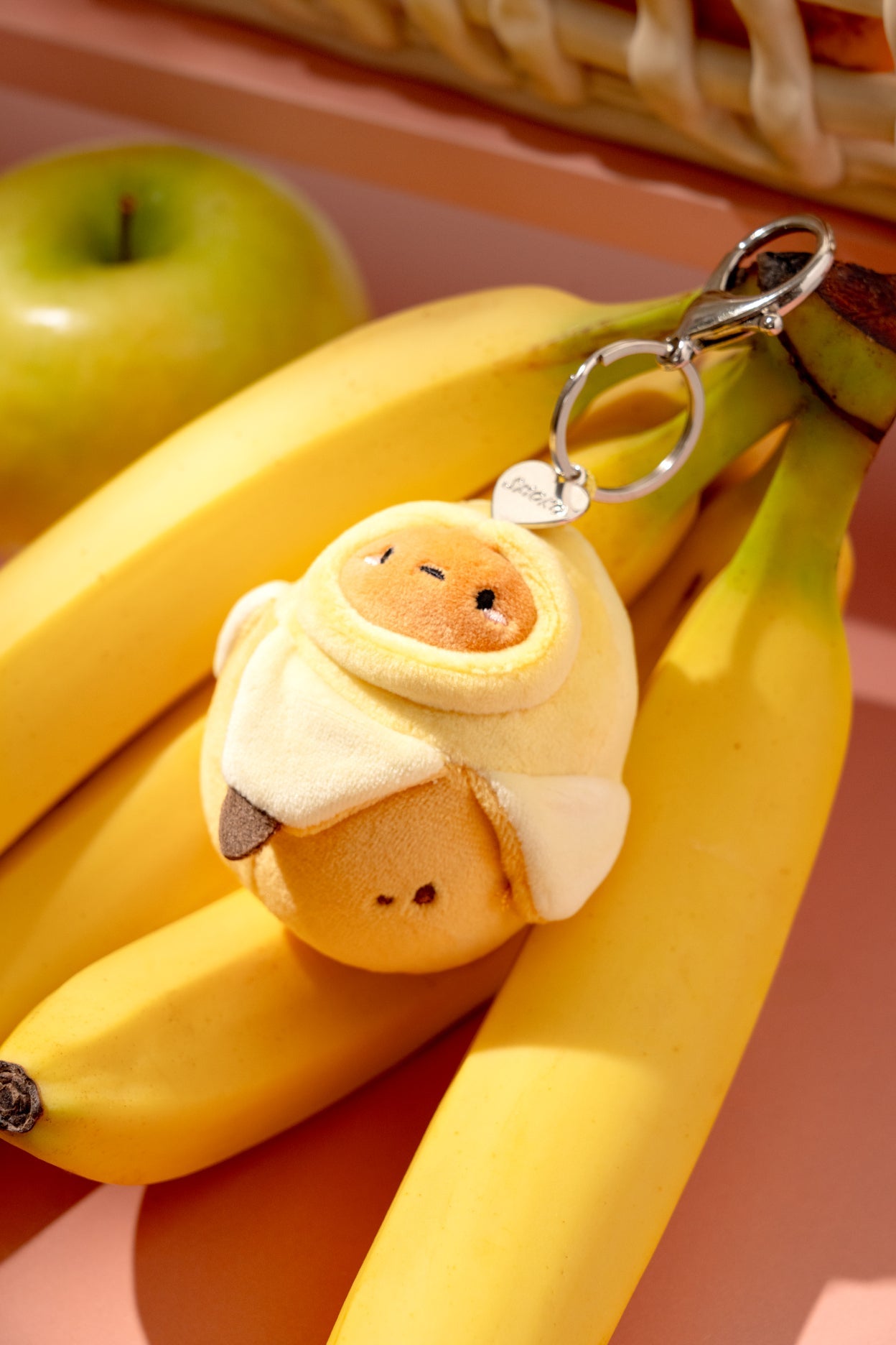Plush keychain shaped like a banana with a face attached to a bunch of bananas.