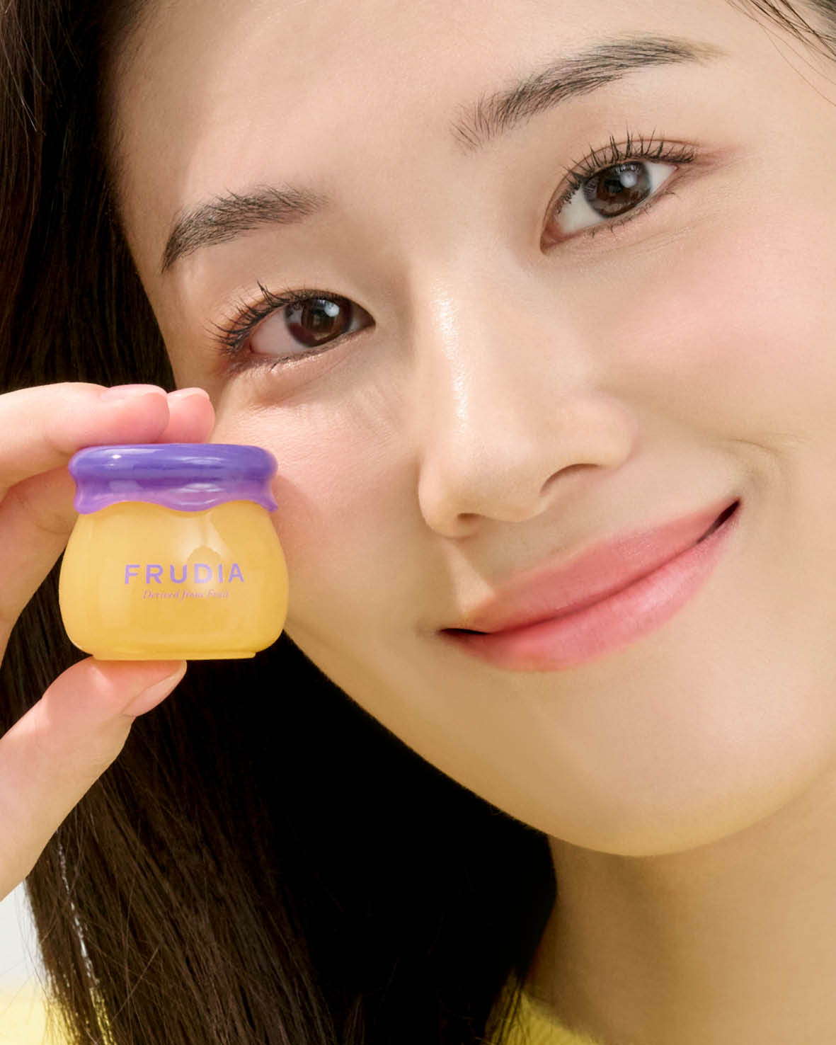 Woman holding a small jar of Frudia skincare.