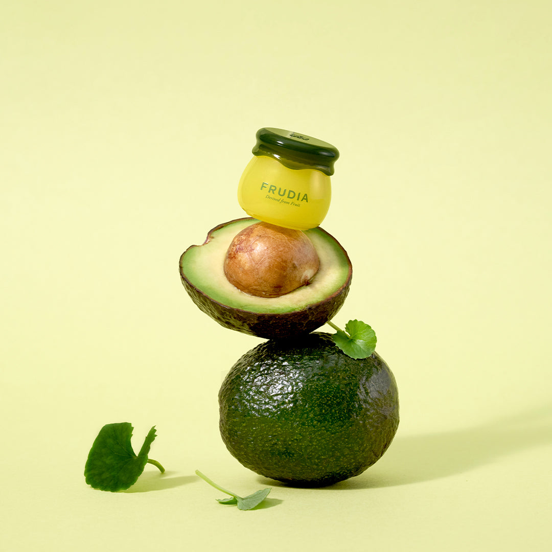 A stack of an avocado, an avocado half, and a Frudia product jar.