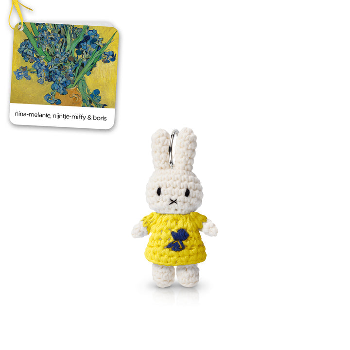 Crocheted Miffy rabbit wearing a yellow dress with blue flower embellishment, a silver keyring loop, and a tag with a Van Gogh painting.