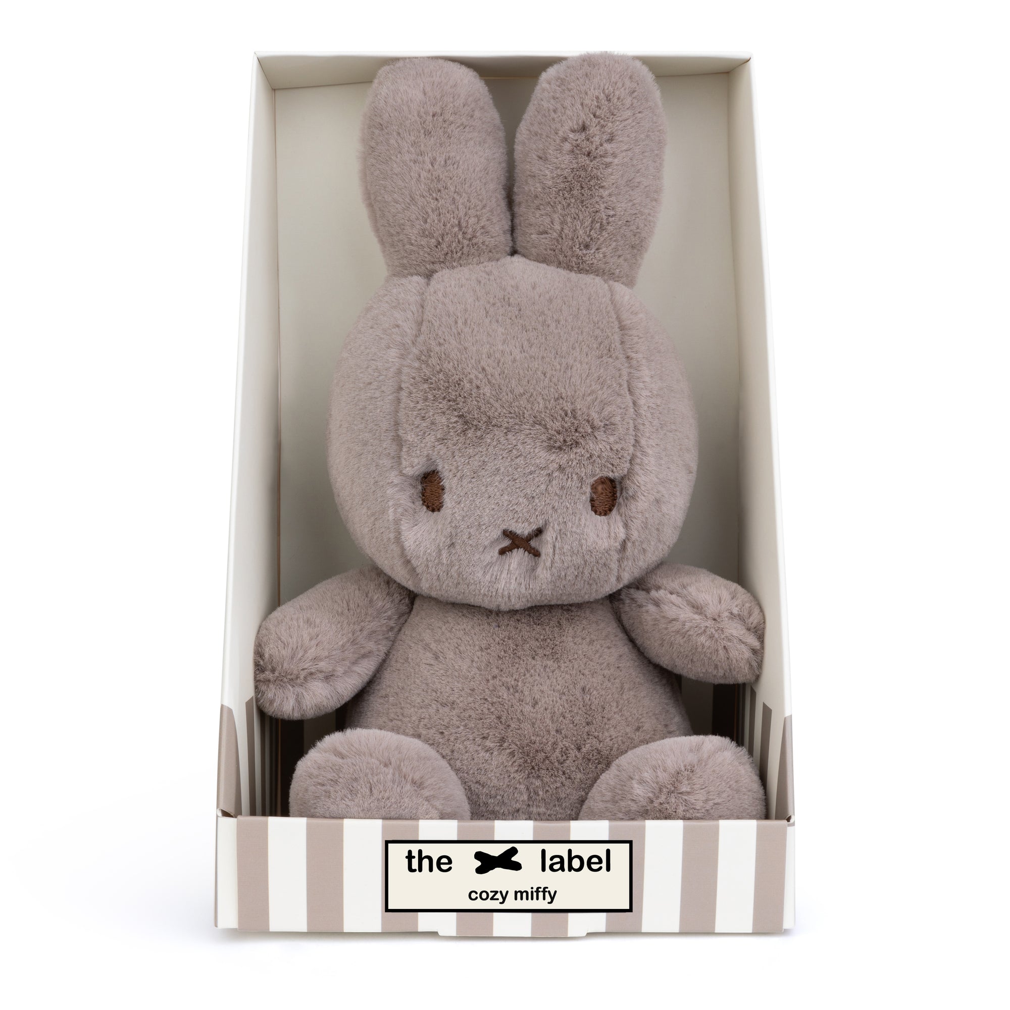 Gray plush bunny toy in striped box.