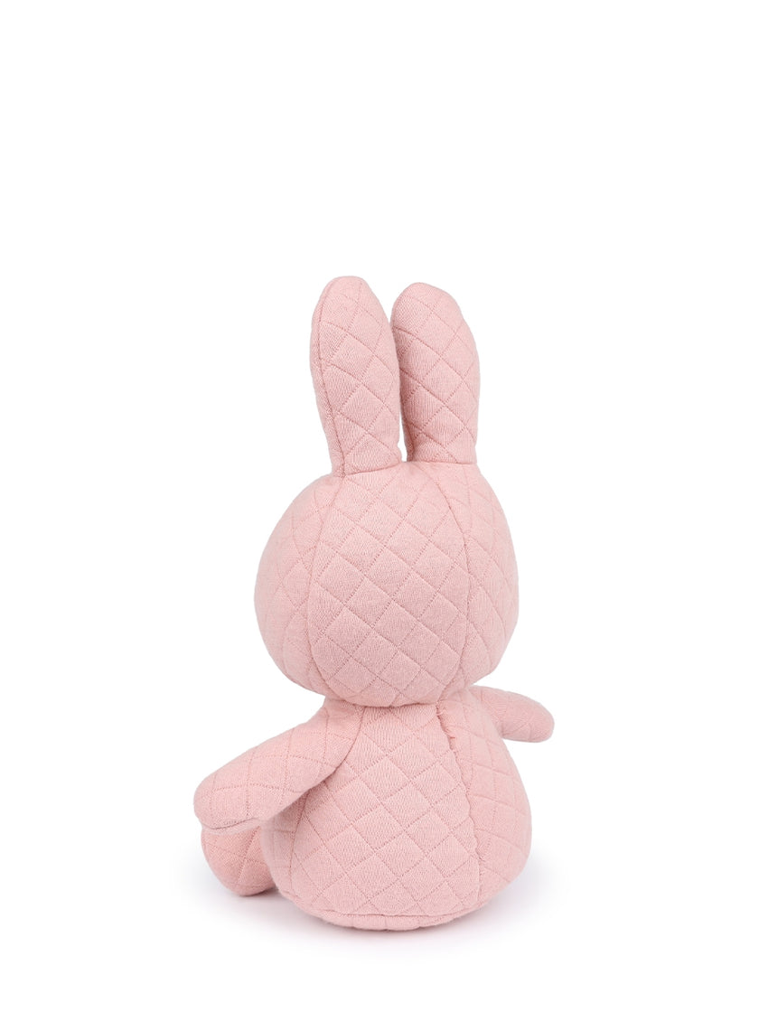 Rear view of a pink, quilted rabbit plush toy sitting upright.