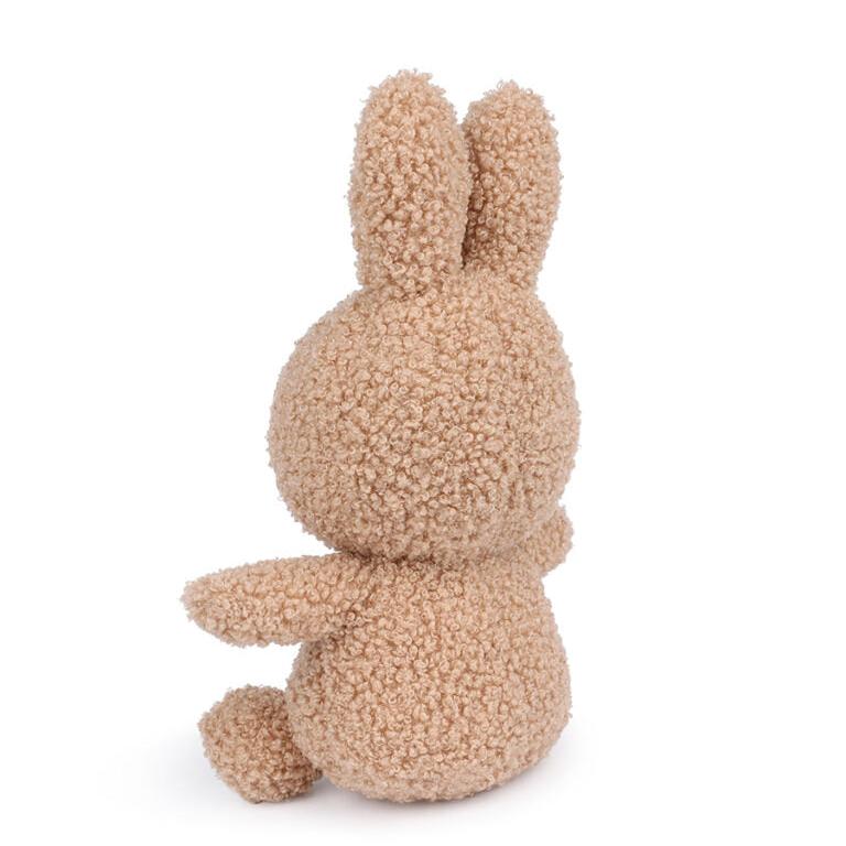Rear view of a tan, curly-textured stuffed bunny.