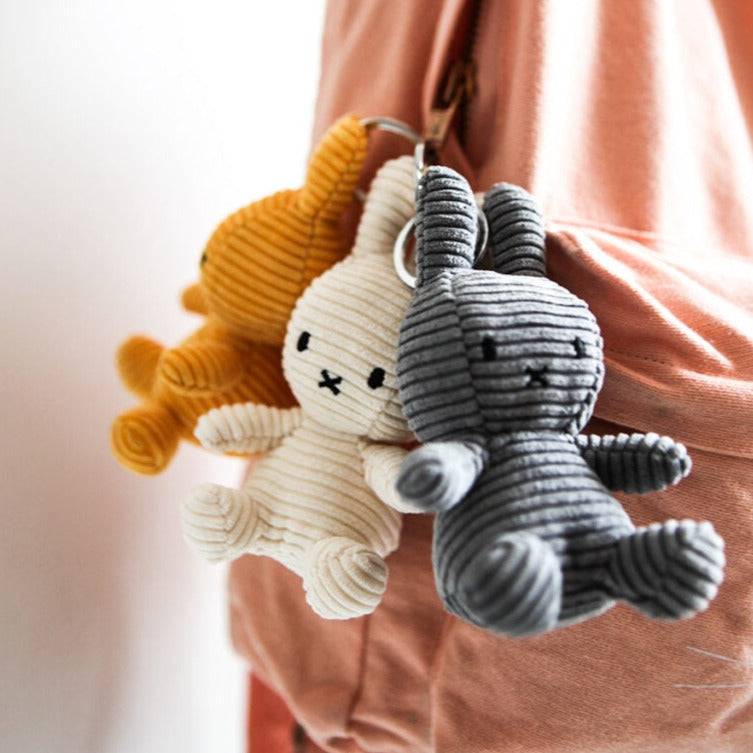 Three corduroy bunny keychains hanging from a pink hoodie.