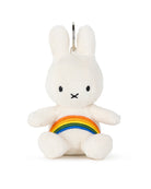 A stuffed white corduroy rabbit with a rainbow on its chest and a key ring on its head.