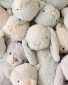 Pile of soft, plush toy animals in muted pastel colors.
