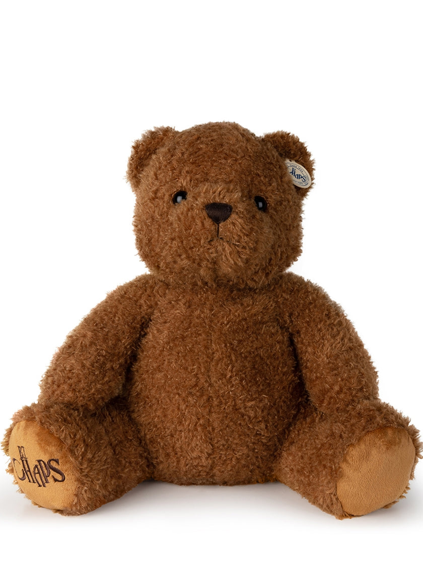 Brown plush teddy bear sitting.