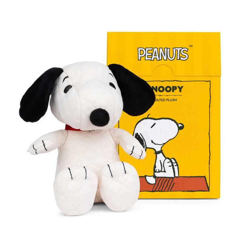 Quilted white Snoopy plush seated next to a yellow box.
