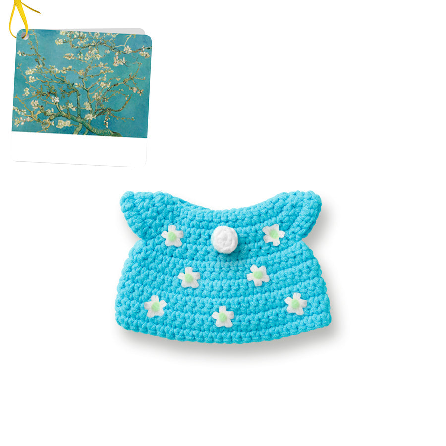 Crocheted blue pet clothing with white flower accents and button.  Van Gogh painting in background.