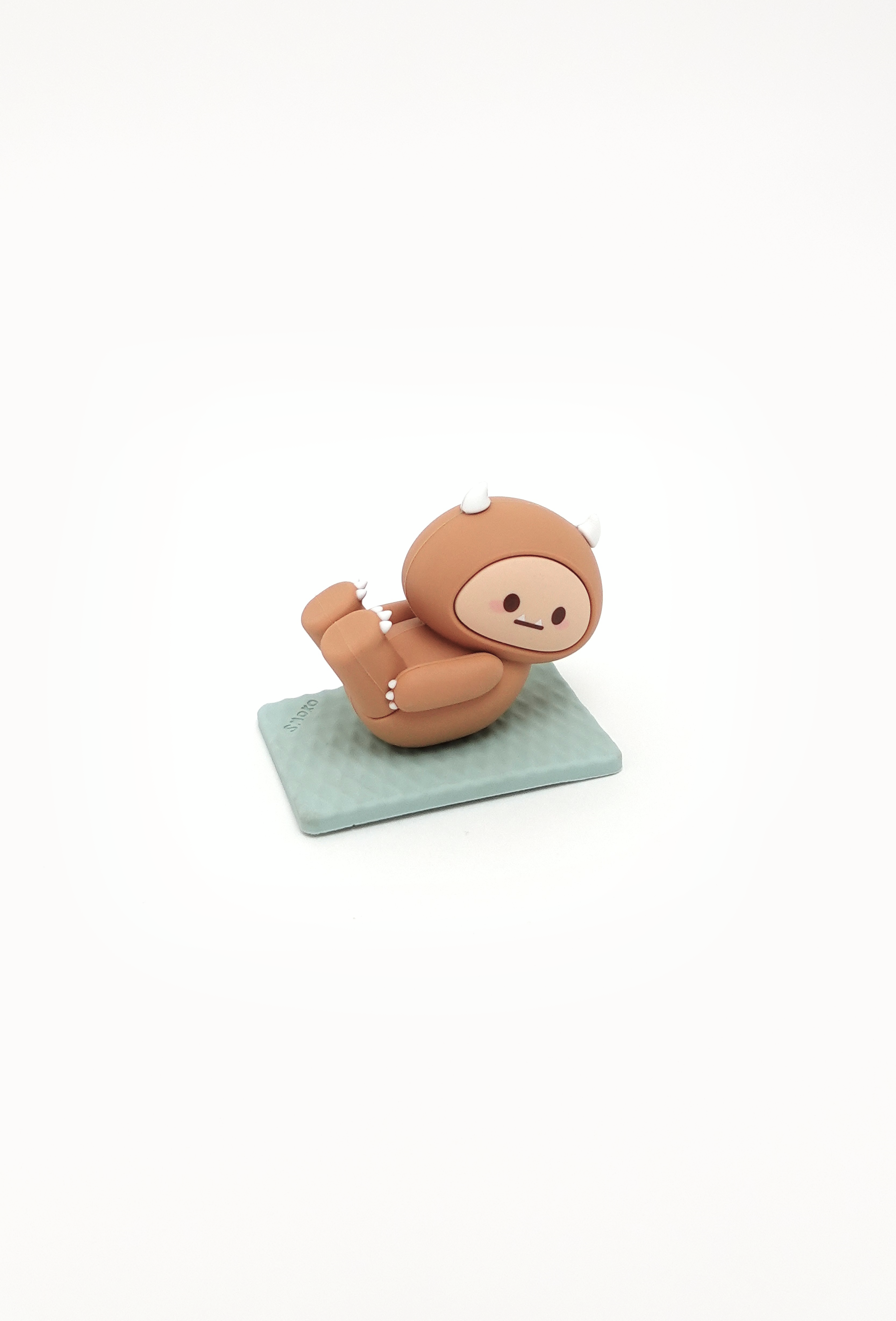 Brown cartoon figurine with horns on a light blue mat.