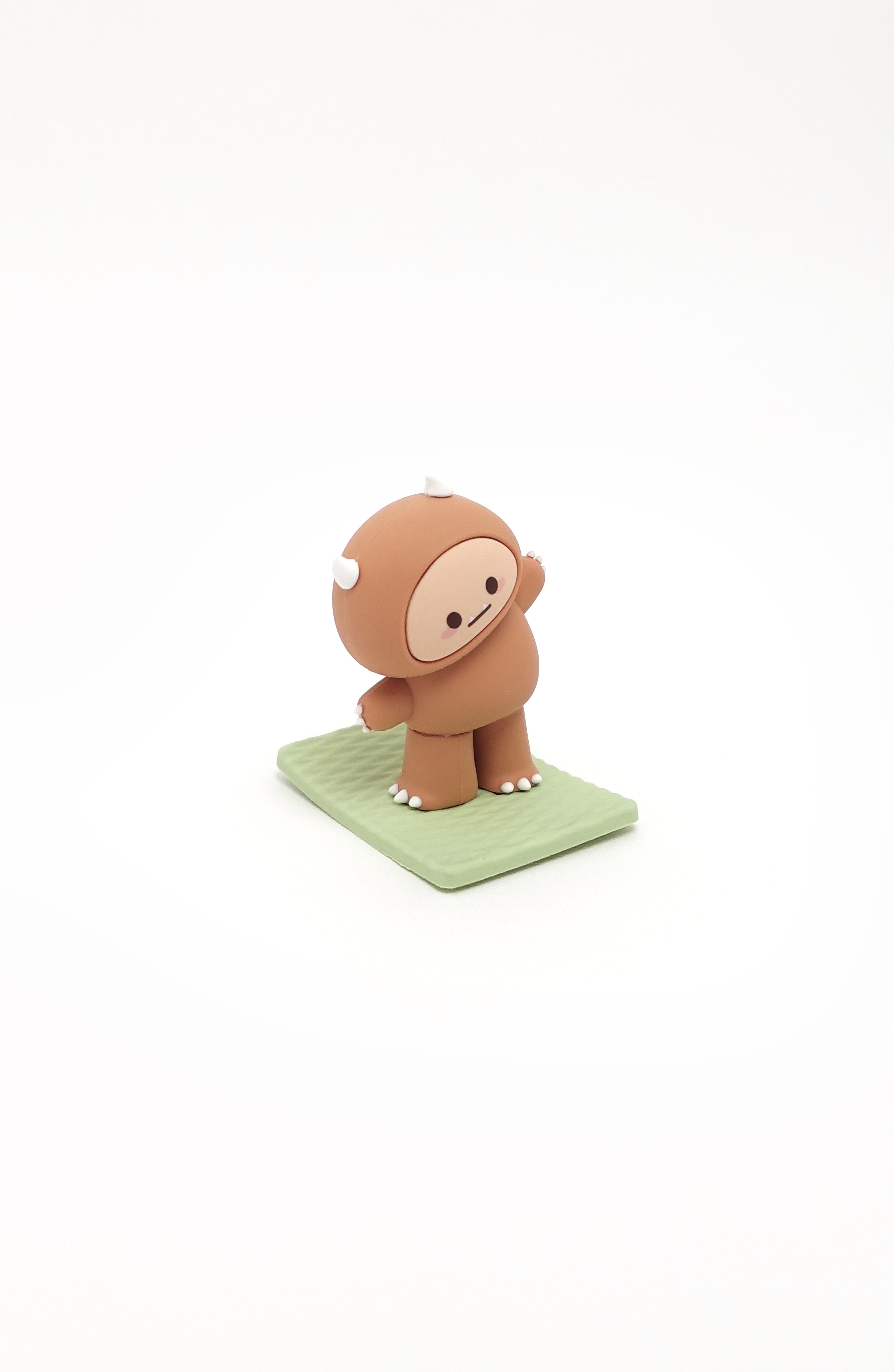 Brown cartoon figurine with white toes, claws, and horns on a green base.
