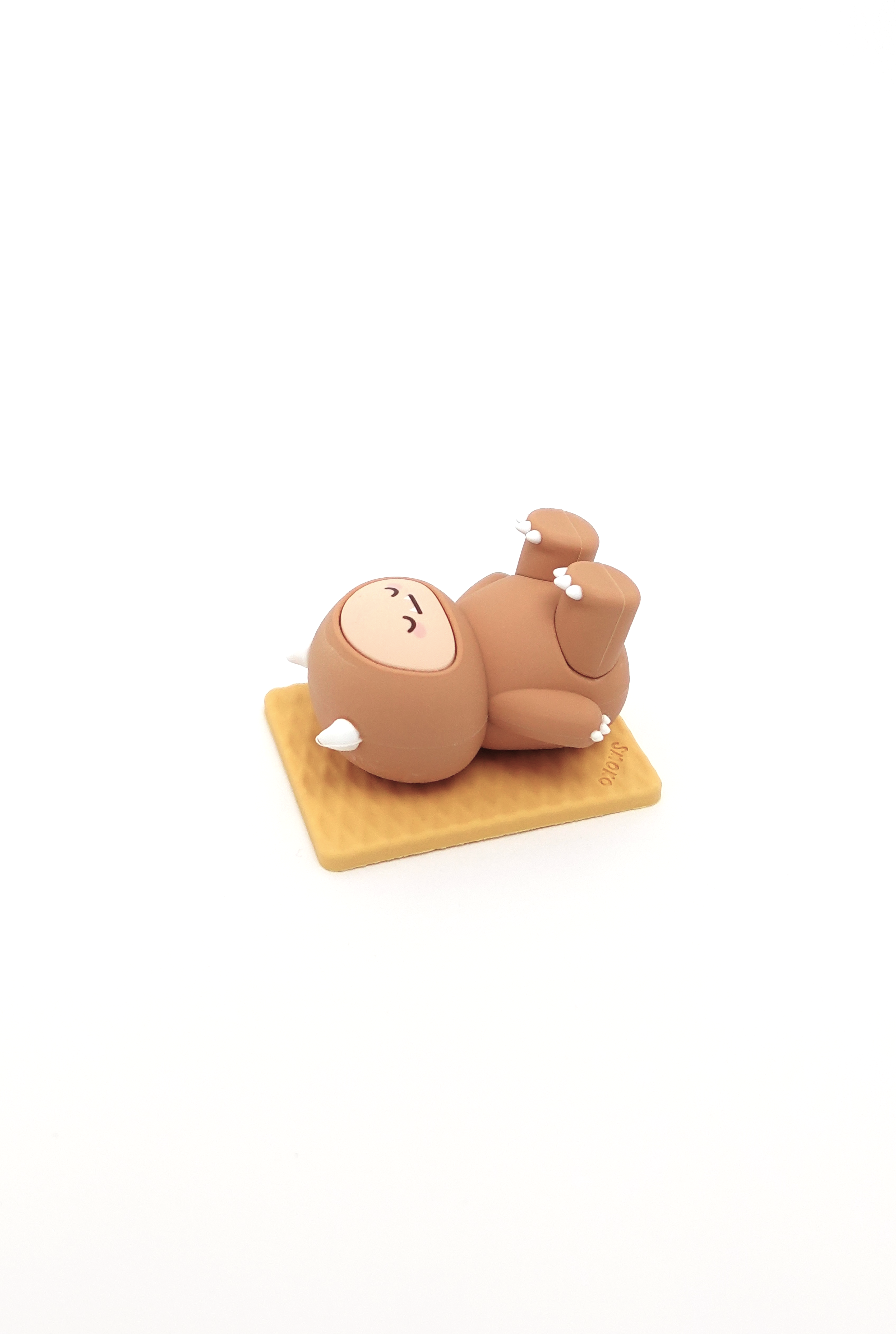 Brown, cartoon sloth figurine lying on a tan square base.