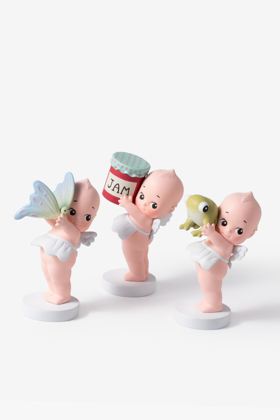 Three baby figurines with a jar of jam on a white background