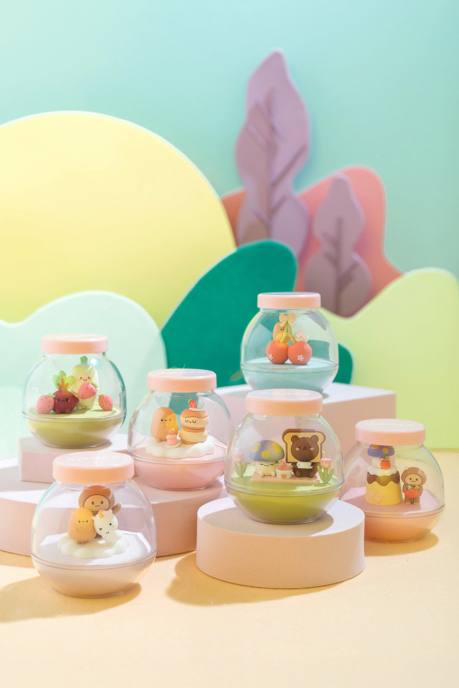 Pastel-colored snow globe-like containers with small figurines on a colorful background