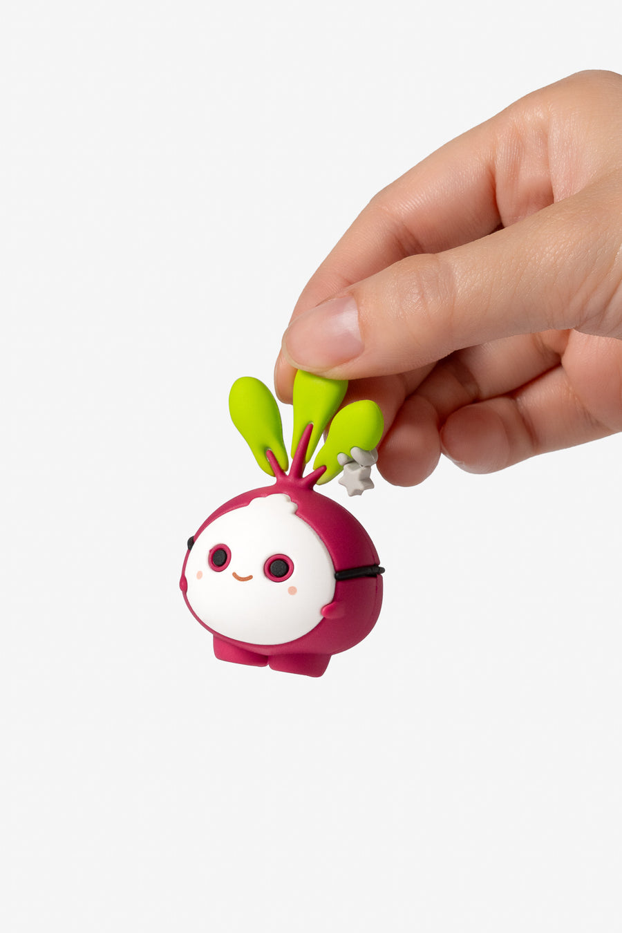A small cartoon radish-shaped keychain or charm being held between a person's fingers against a plain light gray background.