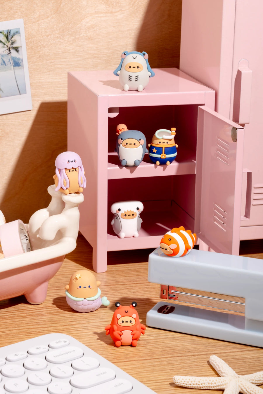 Small figurines in front of a pink locker on a wooden surface