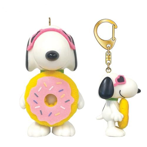 Two Snoopy characters; one in a pink and yellow donut outfit and the other as a gold keychain with a pink sunglass accent.