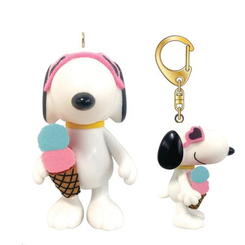 Two Snoopy figurines with ice cream cones. One large white Snoopy wearing pink headphones and a yellow collar holding a blue and pink ice cream cone. The other is smaller, also white, and wearing pink heart-shaped sunglasses and a yellow collar, holding a similar ice cream cone, attached to a gold keychain.