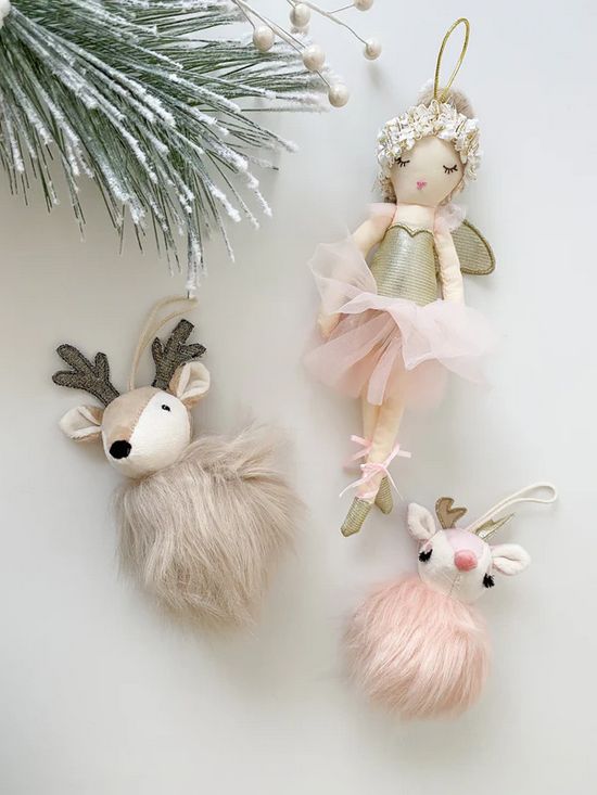 Christmas ornaments: an angel doll with a gold bodice and pink tulle skirt, a beige reindeer with gray antlers and fluffy fur, and a pink reindeer with gold antlers and fluffy fur.