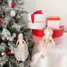 Christmas tree with ornaments, stacked gift boxes, and two ballerina dolls.