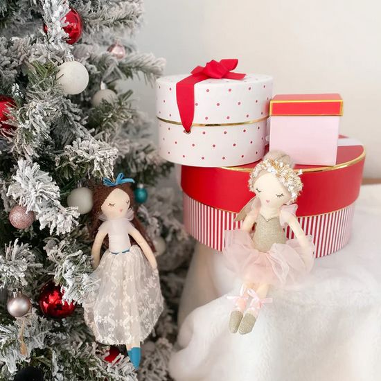 Christmas tree with ornaments, stacked gift boxes, and two ballerina dolls.