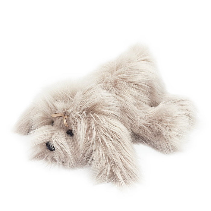 Stuffed, long-haired, light tan dog lying down with a small tan bow on its head.