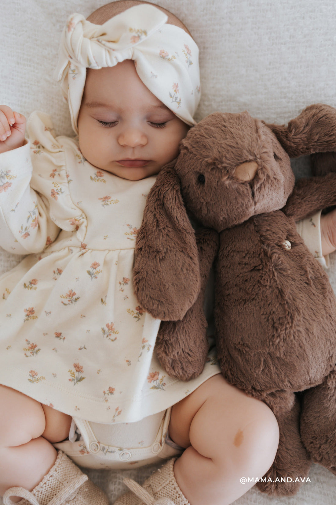 Sleeping baby with floral headband and dress, bunny stuffed animal, knit socks.