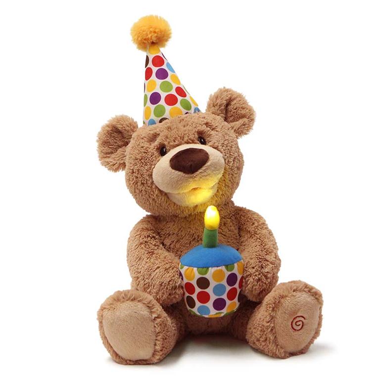 Brown plush teddy bear wearing a polka dot birthday hat and holding a light-up cupcake.