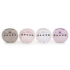 Four small, round, plush cat toys in gray, pink, white, and purple, arranged in a row.