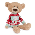 Tan stuffed teddy bear wearing a red, white, and mint green snowman sweater, sitting.