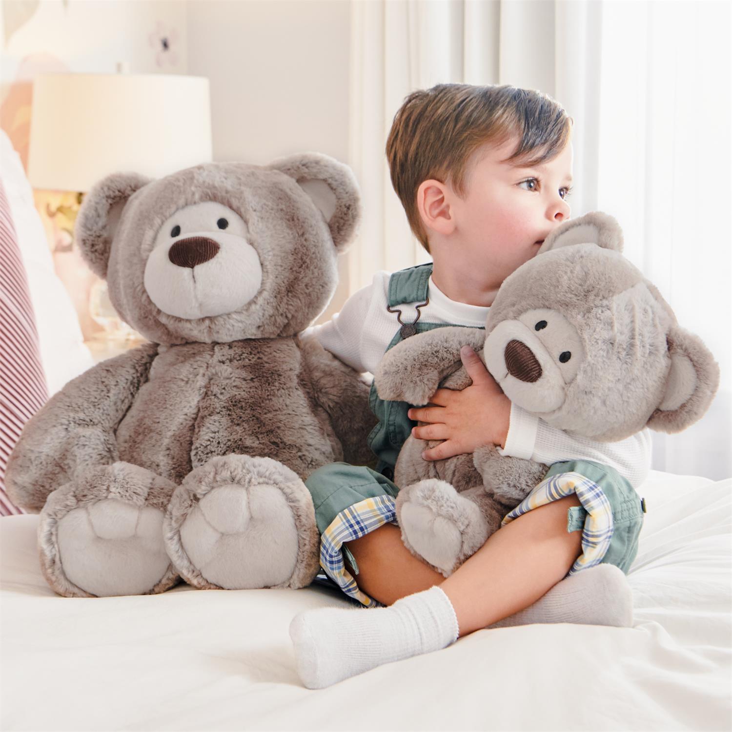 Child holding a large plush teddy bear in a bedroom setting