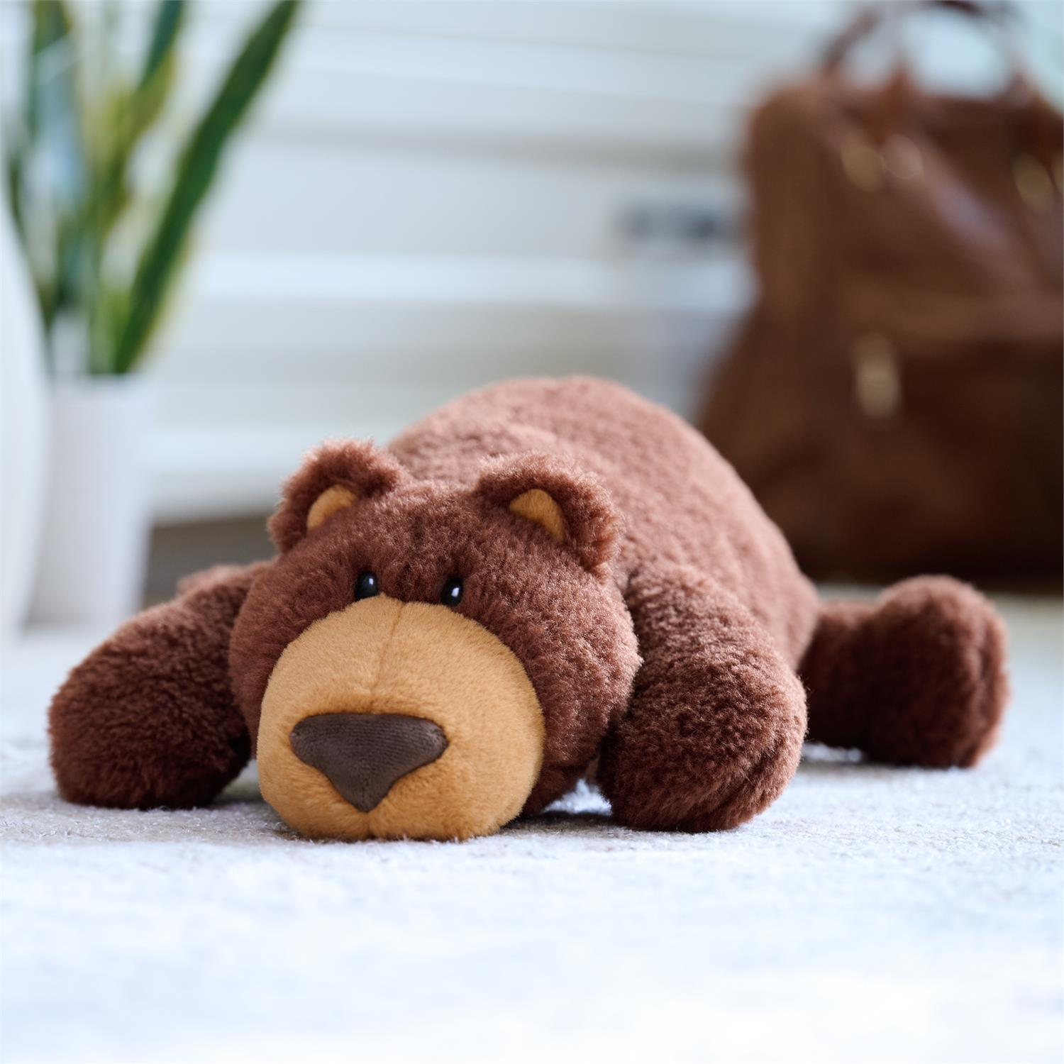 Brown stuffed bear lying down on a white surface.