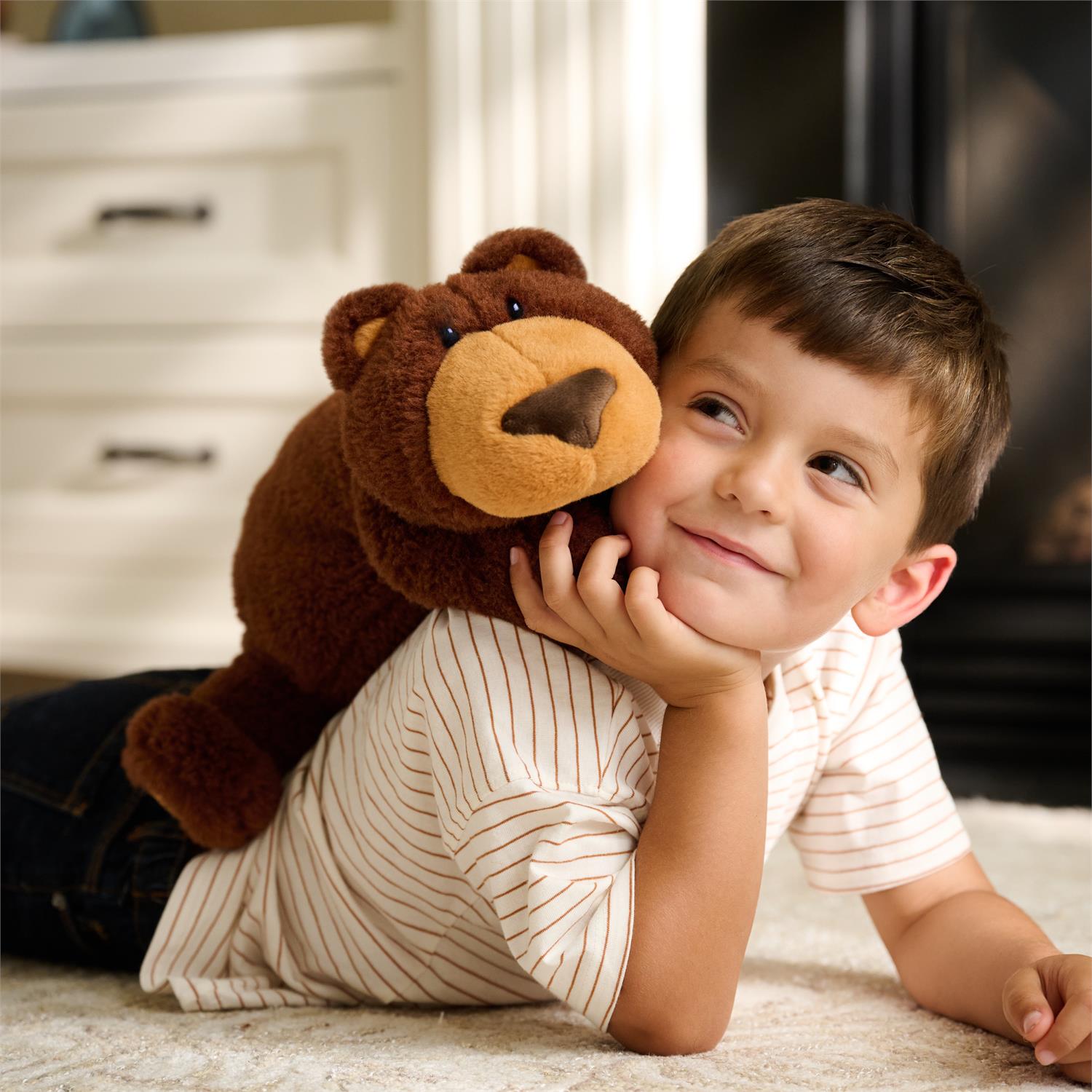 Boy lying on rug with teddy bear.