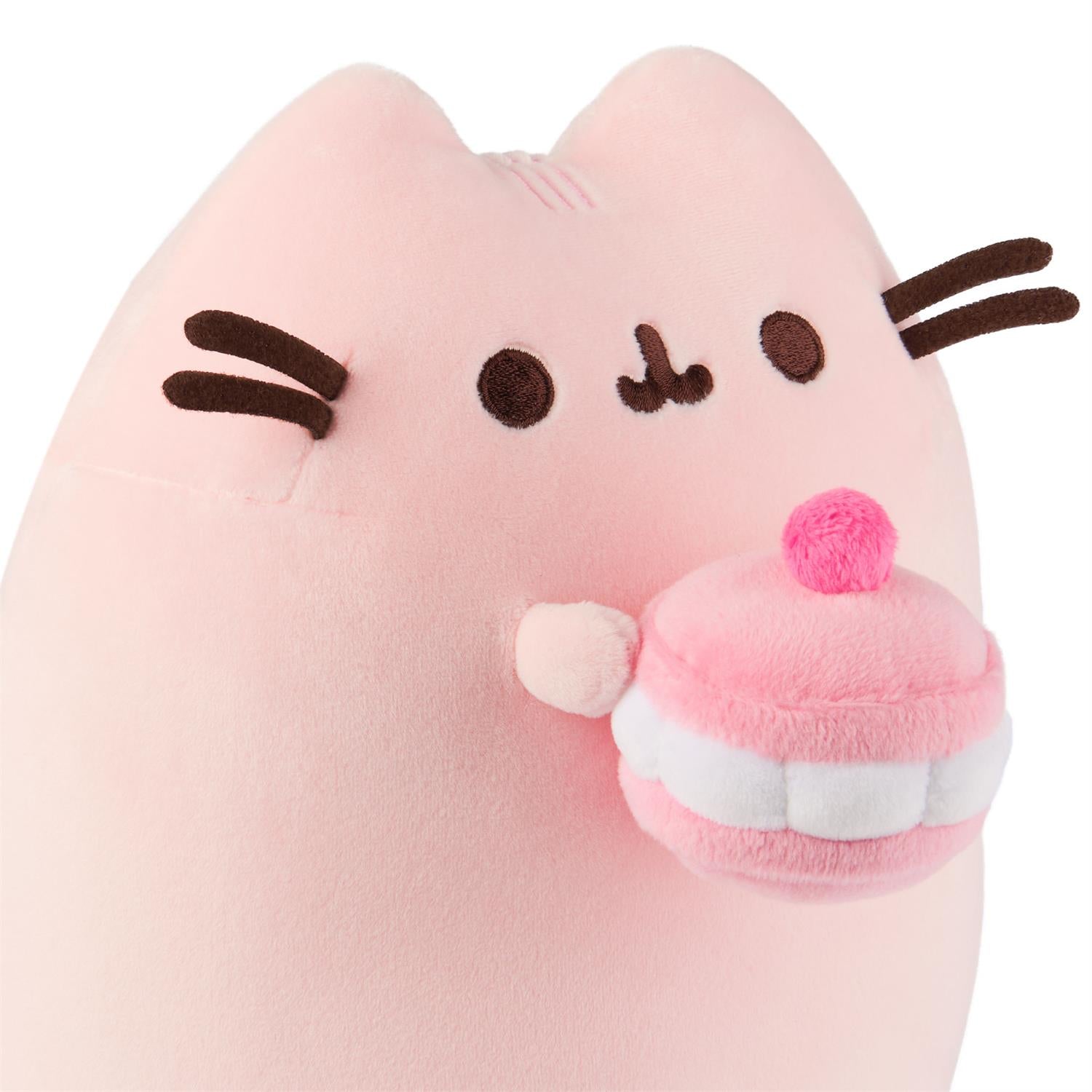 A pink Pusheen plush toy holding a pink plush cupcake.