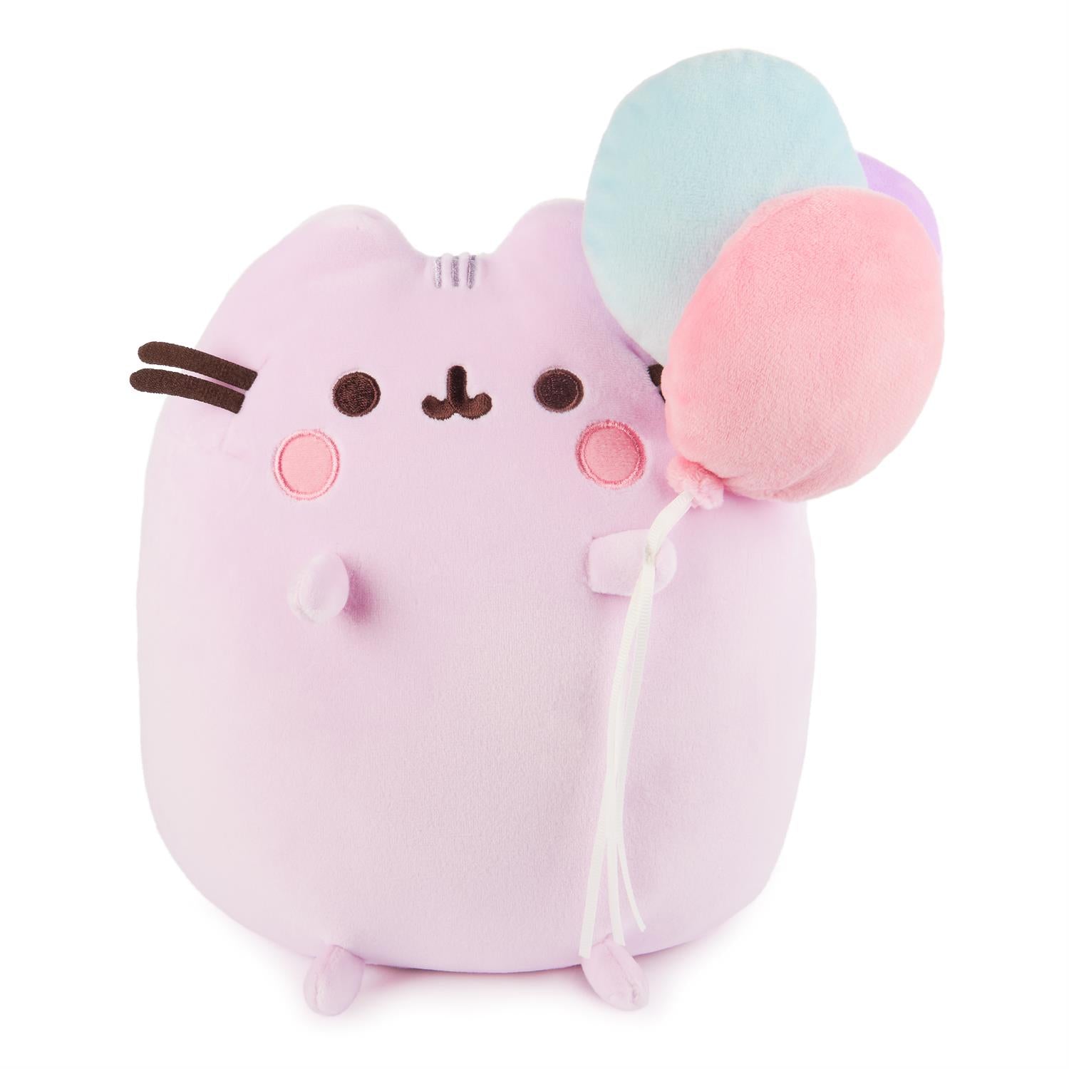 Plush, pink cat toy holding pastel-colored balloons.