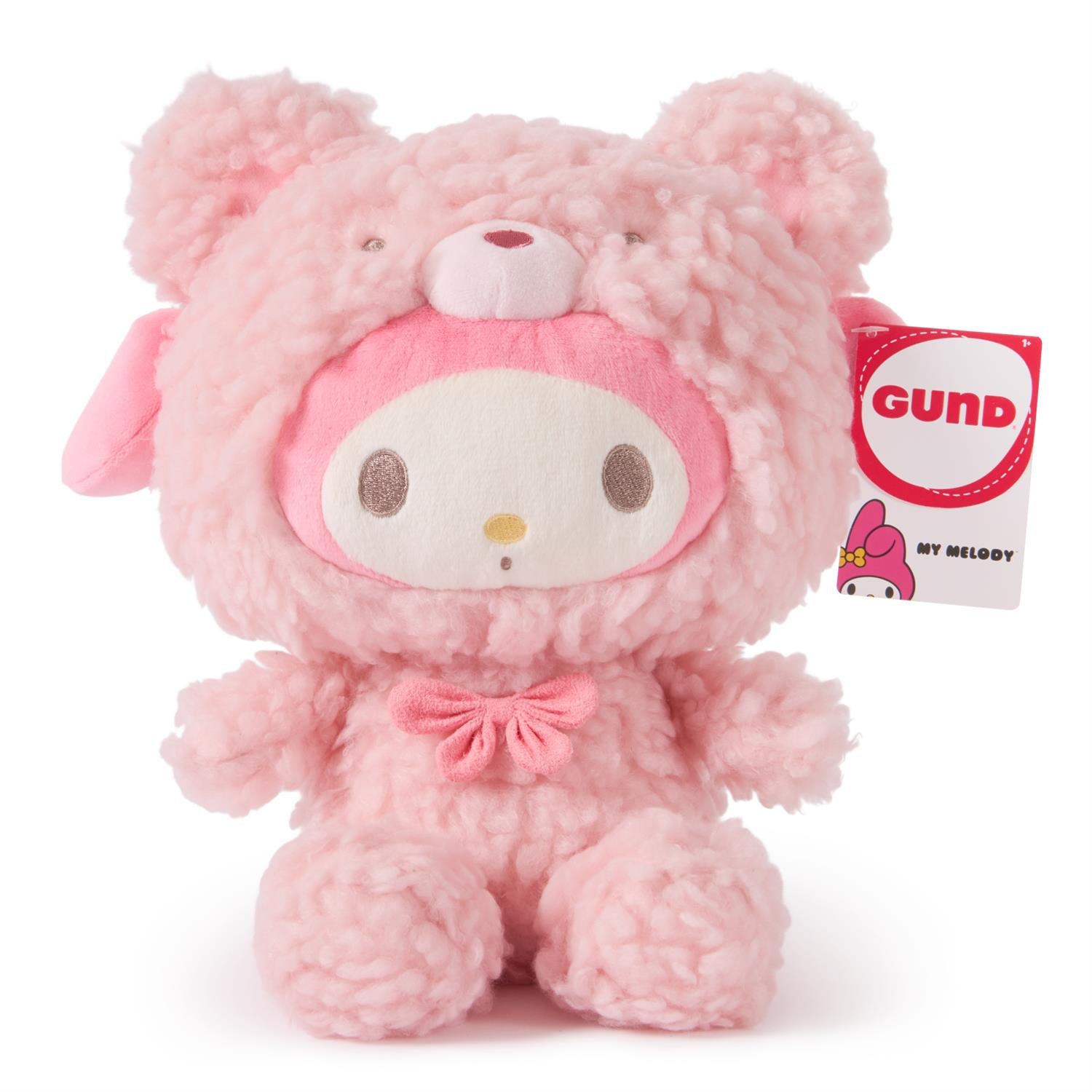 Front view of a seated, plush, pink My Melody toy wearing a hooded bear costume, with a Gund brand tag on its right.